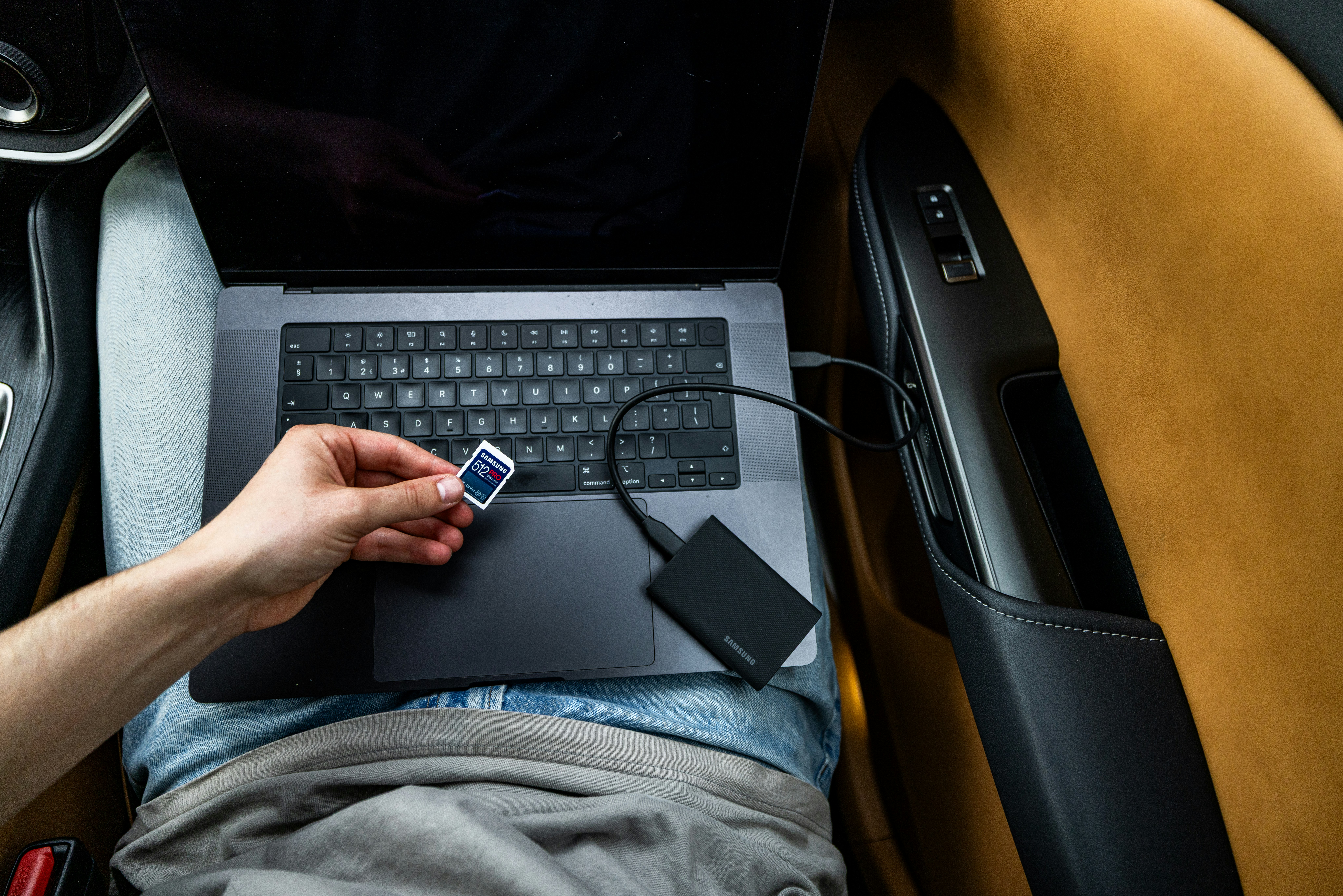 Person inserting an SD card into a laptop connected to an external SSD drive